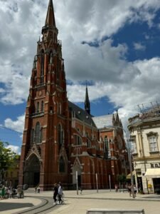 Stunning red brick gothic cathedral under a cloudy sky in a European square.